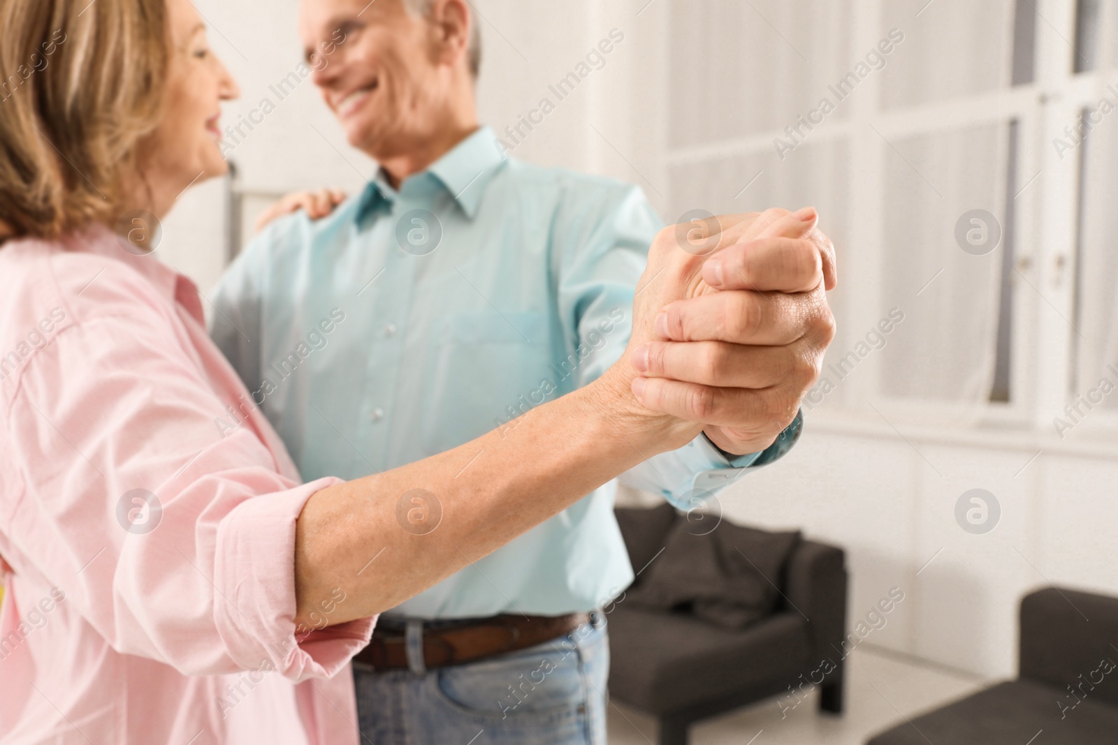 Photo of Happy senior couple dancing together at home, focus on hands