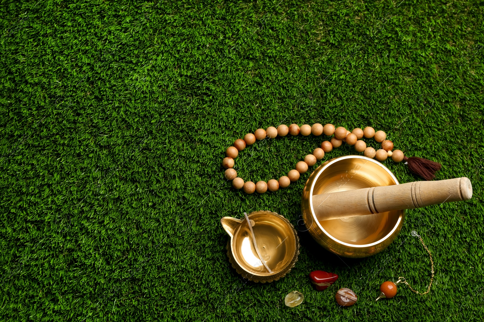 Photo of Flat lay composition with golden singing bowl on green grass, flat lay. Sound healing