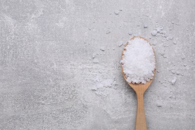 Photo of Spoon with sea salt on light grey table, top view. Space for text