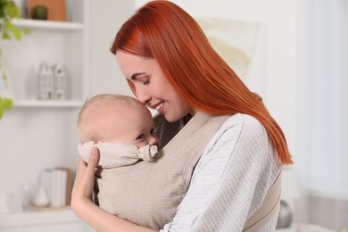 Photo of Mother holding her child in sling (baby carrier) at home