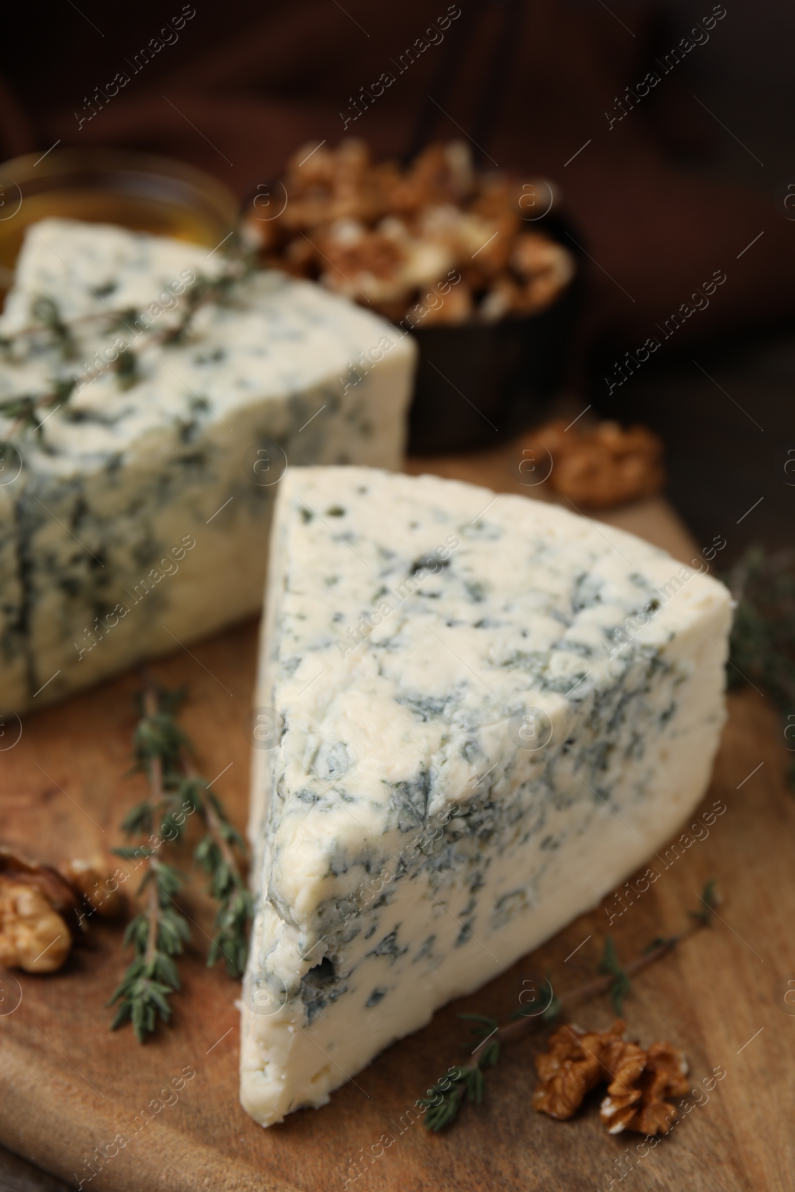 Photo of Tasty blue cheese with thyme and walnuts on wooden table, closeup