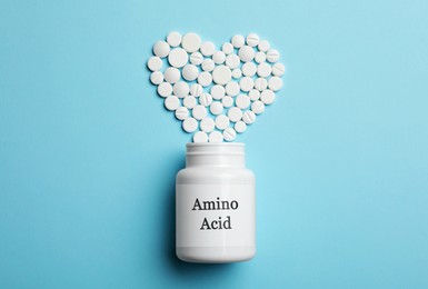 Image of Plastic bottle with Amino Acid Complex and pills on light blue background, flat lay