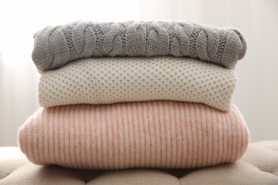 Stack of folded warm sweaters on couch indoors, closeup