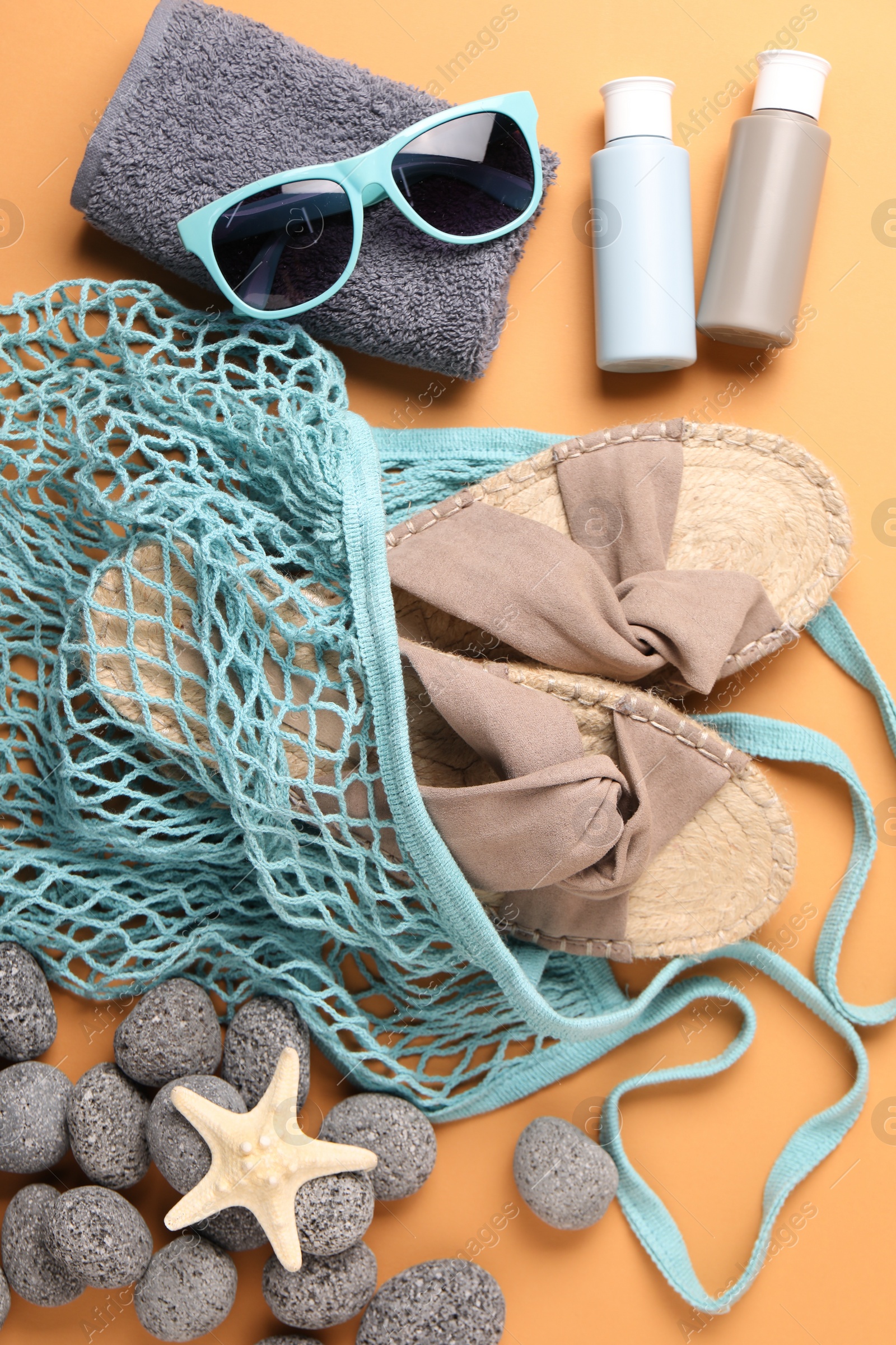 Photo of String bag and different beach accessories on pale orange background, flat lay