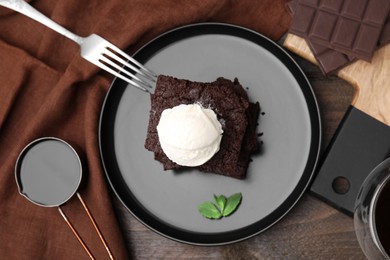 Tasty brownies served with ice cream on wooden table, flat lay