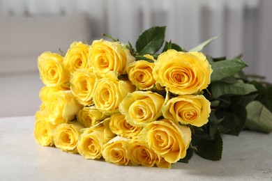 Photo of Beautiful bouquet of yellow roses on light grey table indoors, closeup