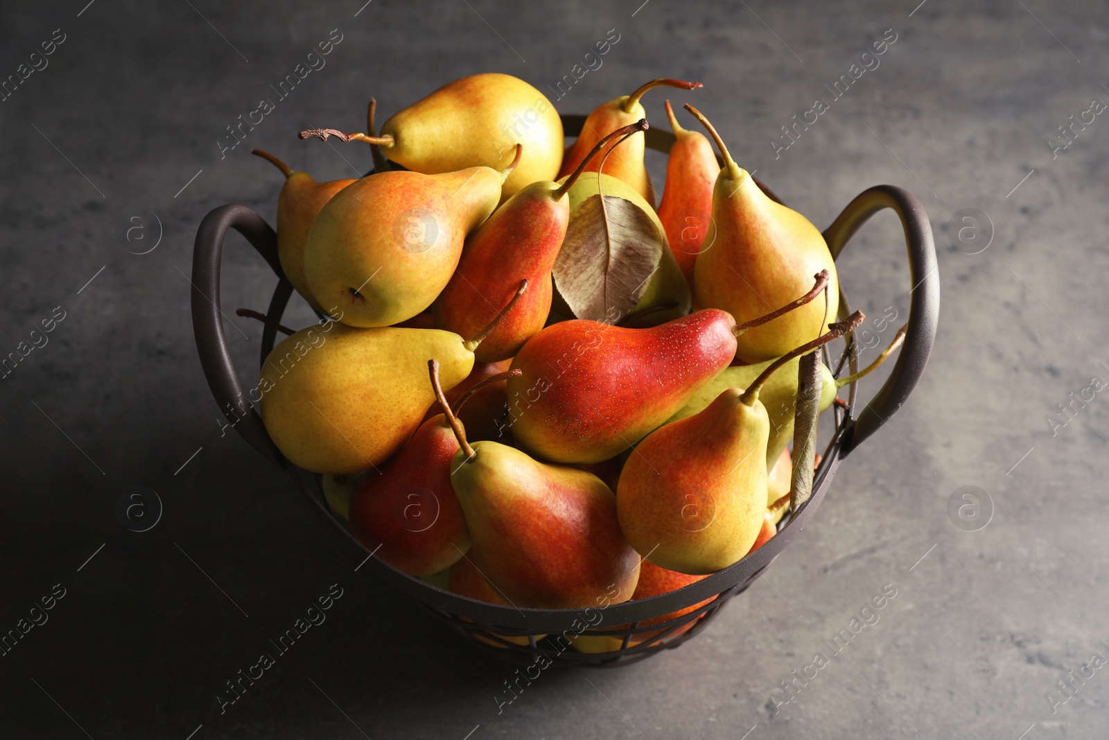 Photo of Basket with ripe pears on grey background