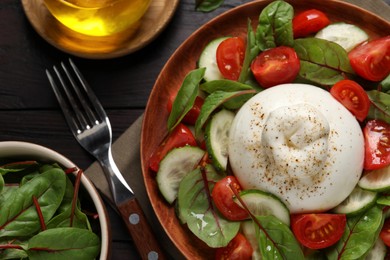 Photo of Delicious burrata salad served on wooden table, flat lay