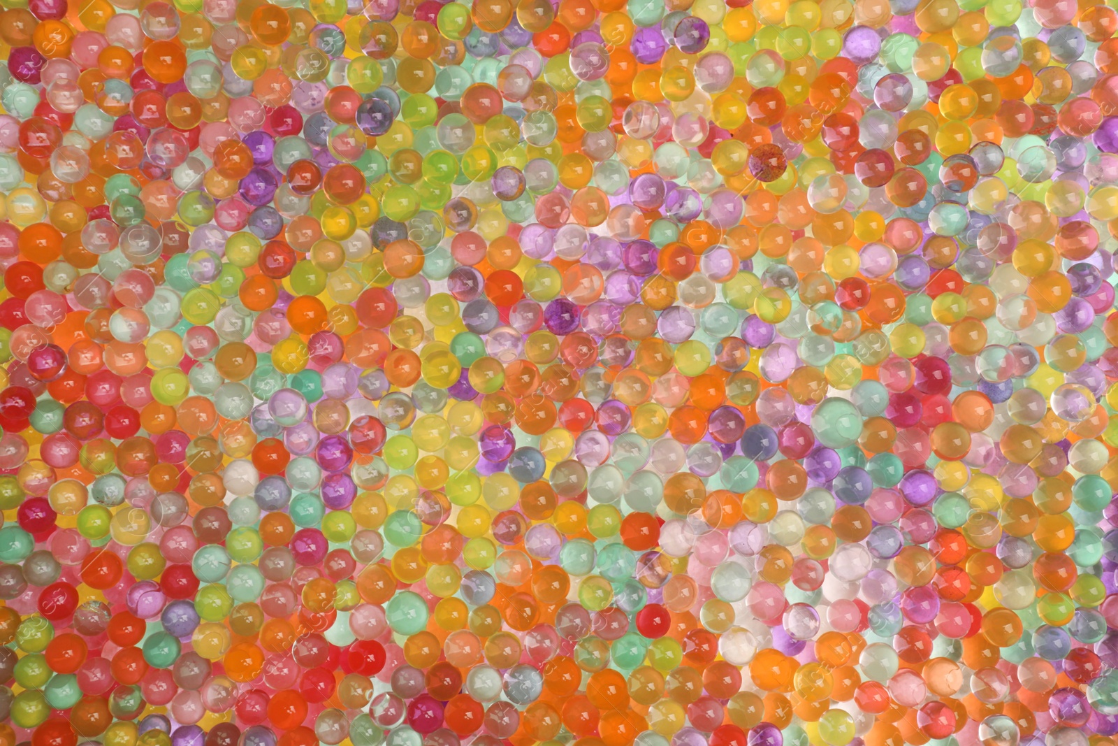 Photo of Closeup view of different color vase fillers as background. Water beads