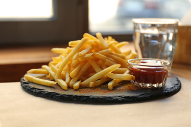 Photo of Tasty French fries with red sauce served on table in cafe