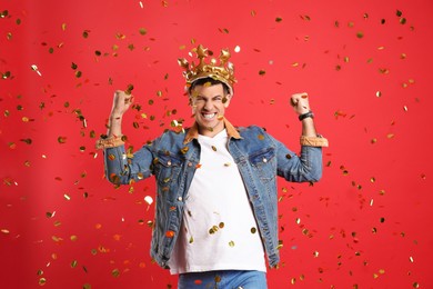 Photo of Happy man in party crown and confetti on red background