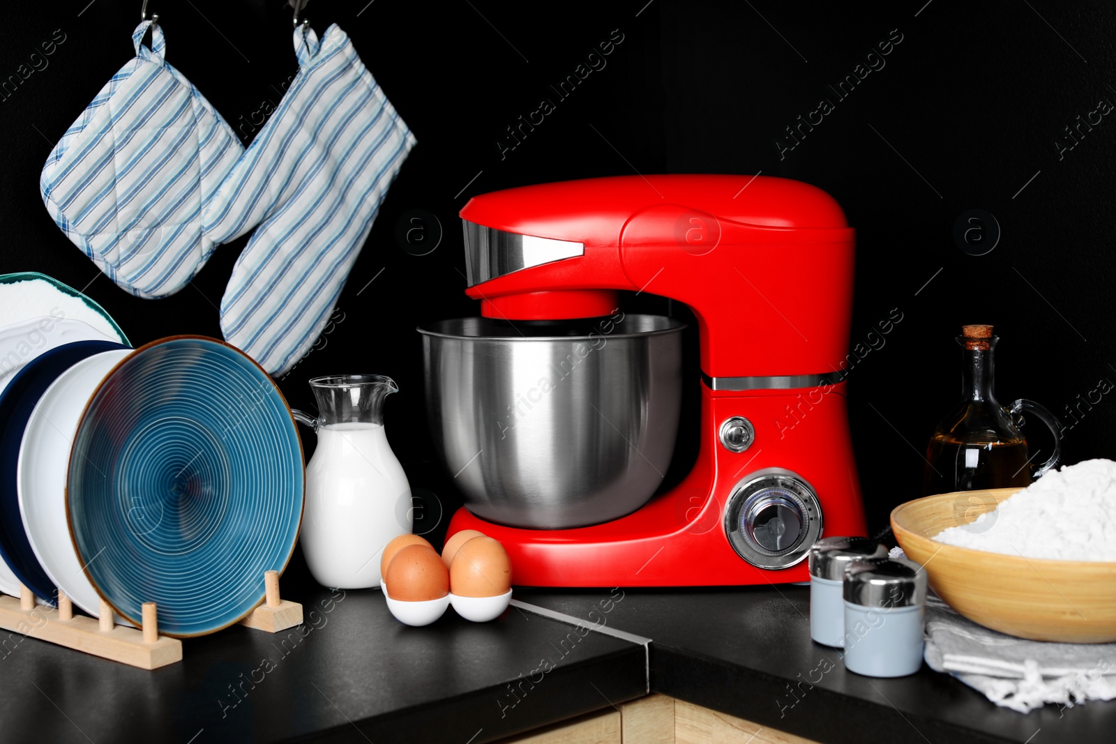 Photo of Modern stand mixer, dishware and ingredients on countertop in kitchen