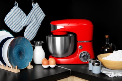 Photo of Modern stand mixer, dishware and ingredients on countertop in kitchen