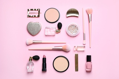 Makeup brushes and cosmetic products on pink background, flat lay