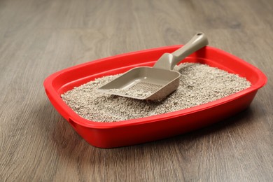Photo of Cat litter tray with filler and scoop on wooden floor