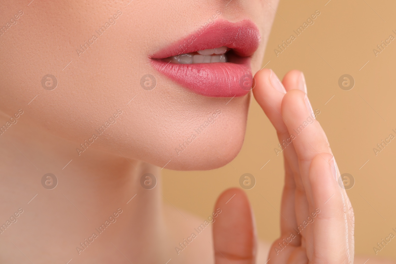 Photo of Young woman with beautiful full lips on beige background, closeup