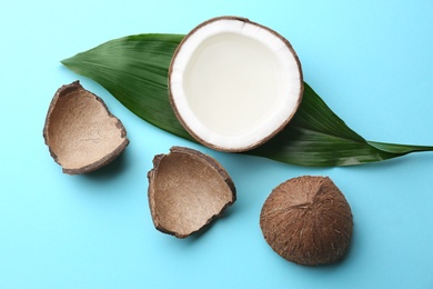 Fresh coconuts and palm leaf on light blue background, flat lay