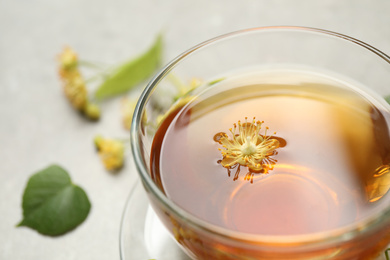 Photo of Cup of tea with linden blossom on table, closeup