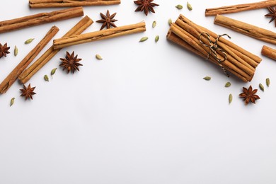 Photo of Cinnamon sticks, star anise and cardamom pods on white background, flat lay. Space for text