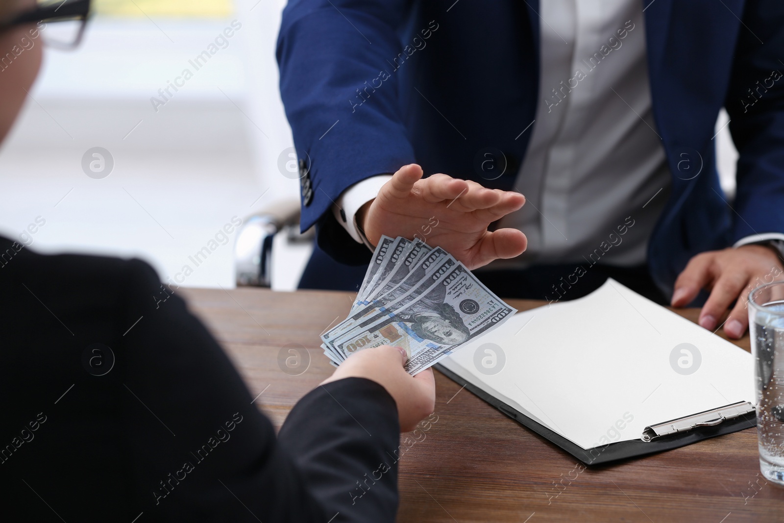 Photo of Businessman refuses to take bribe money at wooden table, closeup