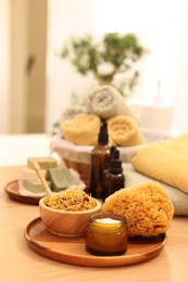 Photo of Dry flowers, loofah and jar with cream on wooden table indoors, space for text. Spa time