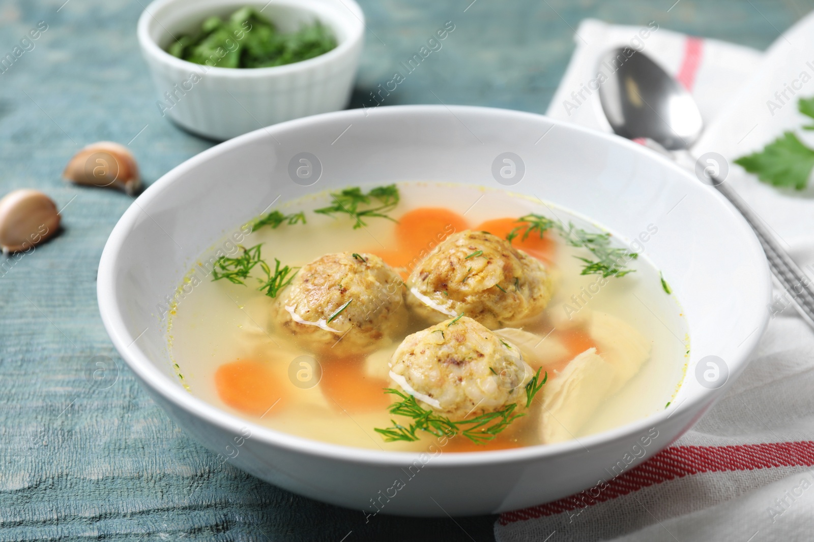 Photo of Bowl of Jewish matzoh balls soup on color wooden table