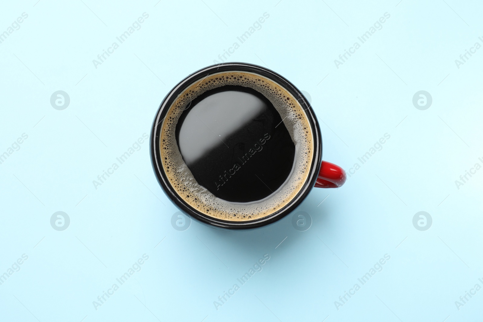 Photo of Aromatic coffee in cup on light blue background, top view