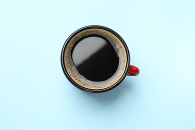 Aromatic coffee in cup on light blue background, top view