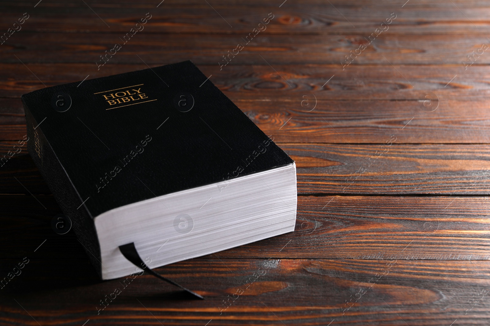 Photo of Bible with black cover on wooden table. Christian religious book