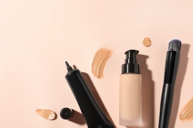 Photo of Liquid foundations, swatches and makeup brush on beige background, flat lay. Space for text