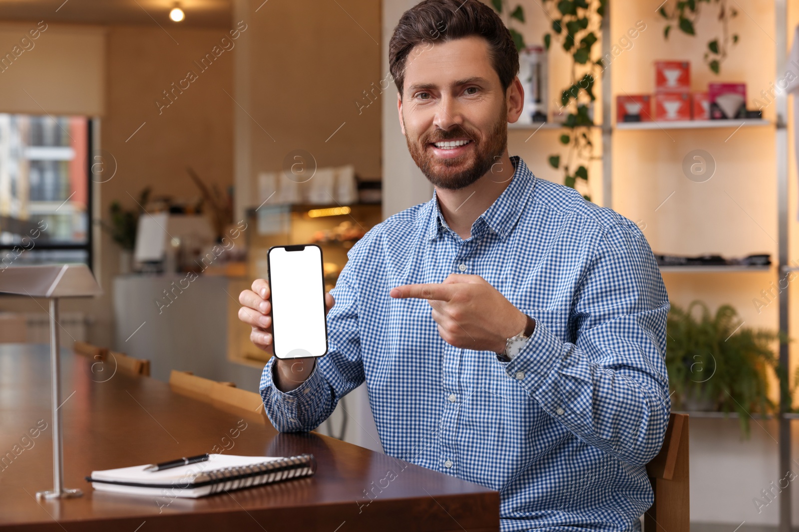 Photo of Handsome man showing his smartphone in cafe