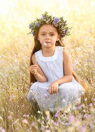 Cute little girl wearing flower wreath outdoors. Child spending time in nature