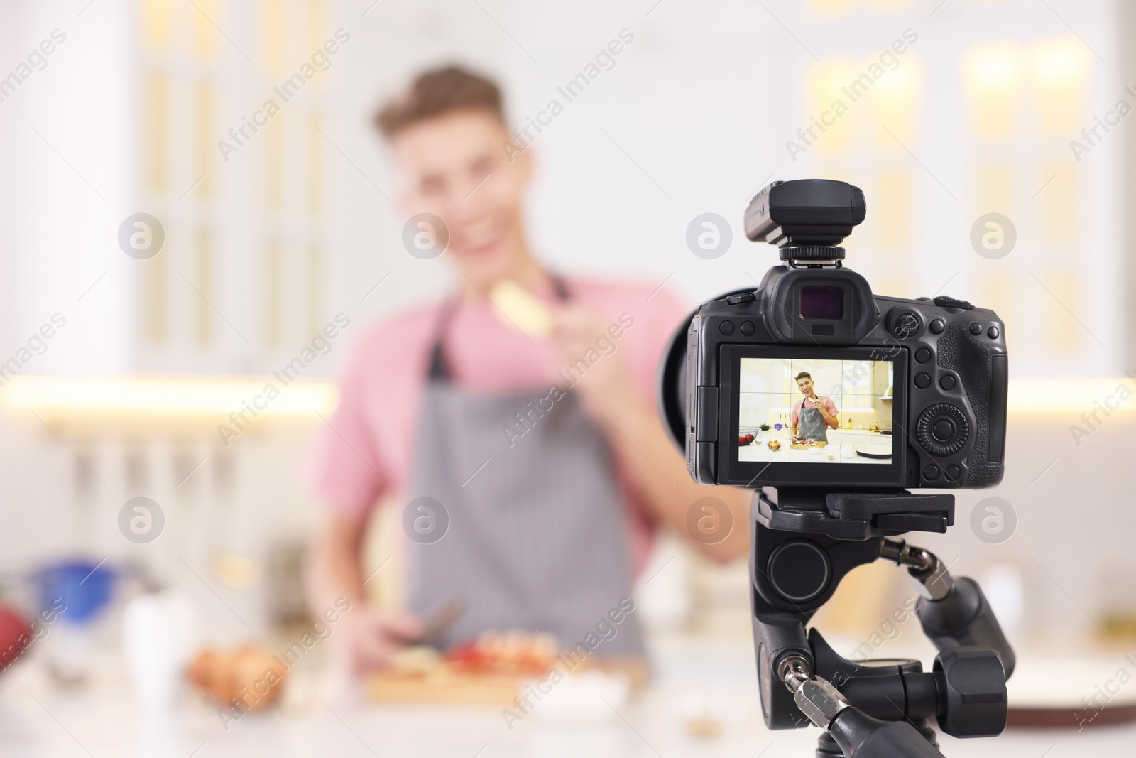 Photo of Food blogger recording video in kitchen, focus on camera