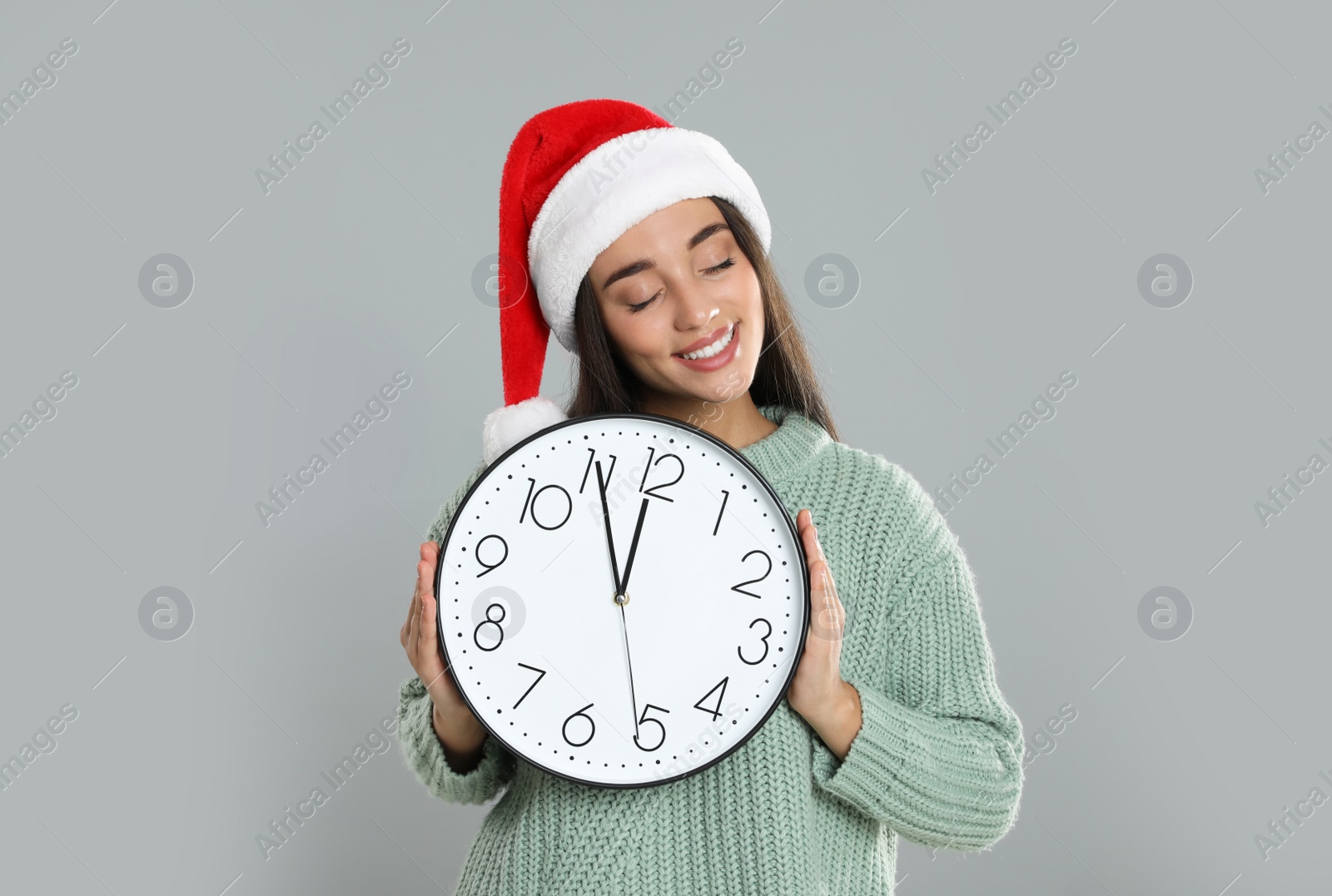 Photo of Woman in Santa hat with clock on grey background. New Year countdown