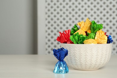 Photo of Candies in colorful wrappers on light table, space for text