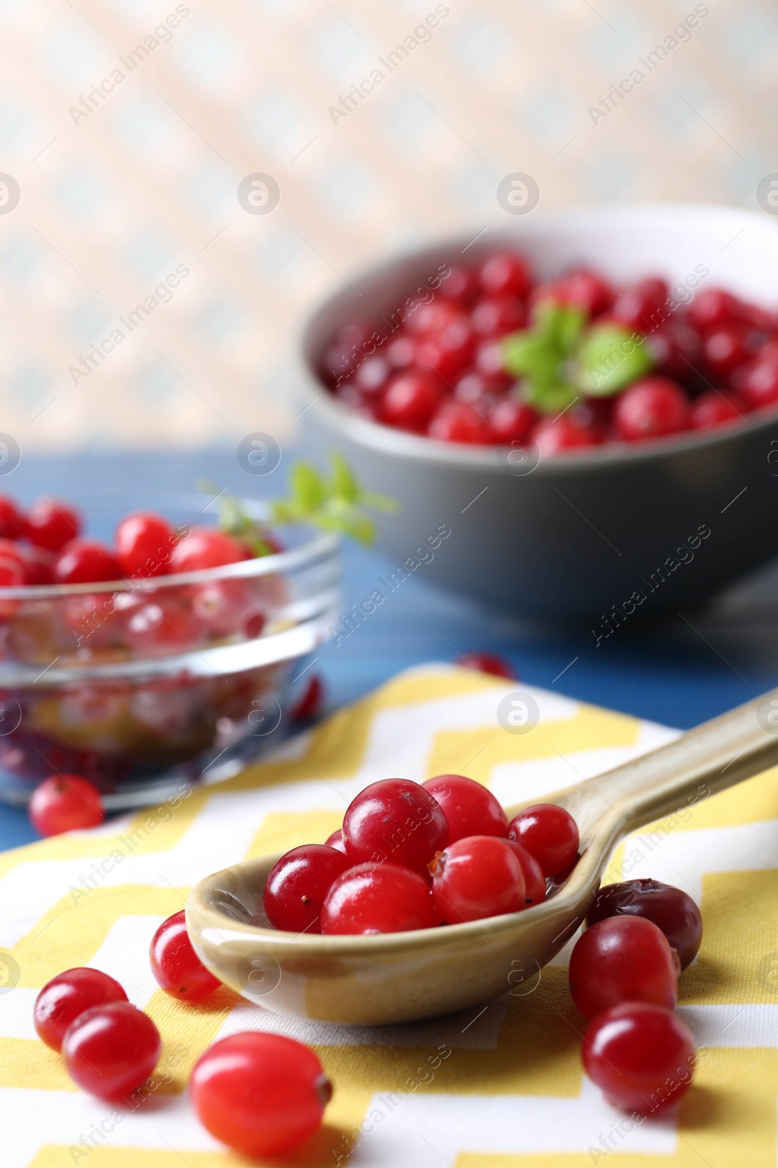 Photo of Spoon with fresh ripe cranberries on table, closeup