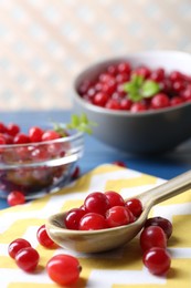 Photo of Spoon with fresh ripe cranberries on table, closeup