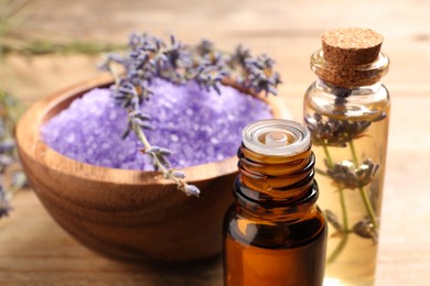 Bowl of sea salt, essential oil and lavender flowers on wooden table, closeup