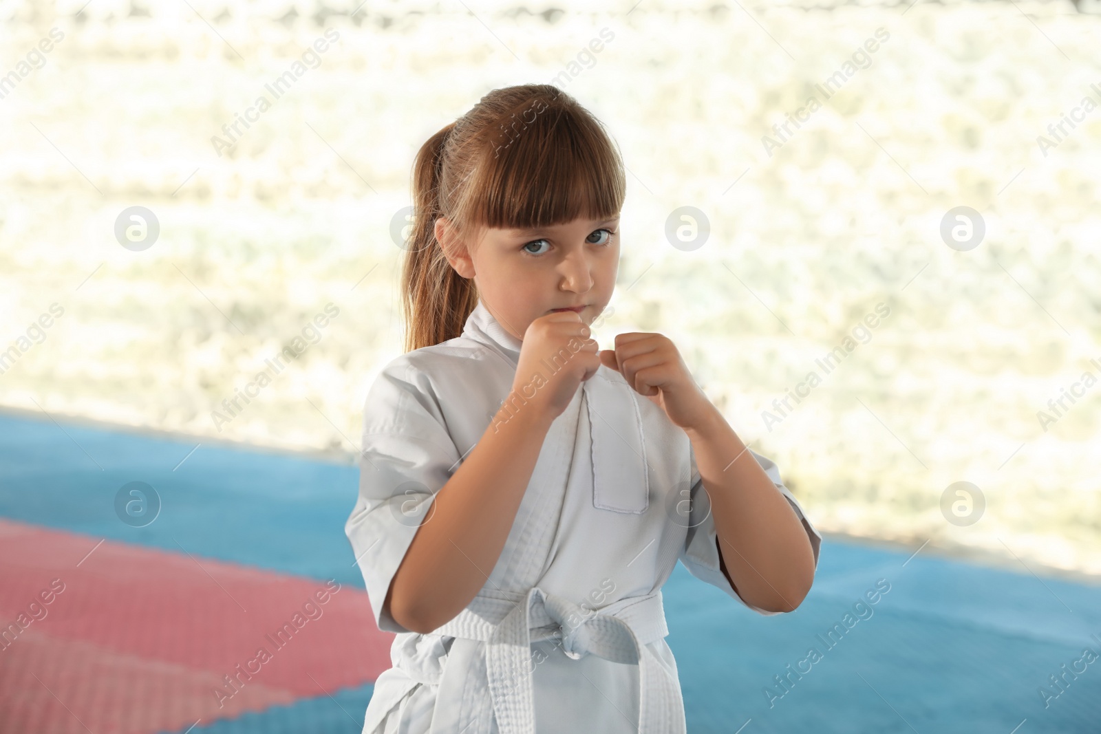 Photo of Girl in kimono practicing karate on tatami outdoors