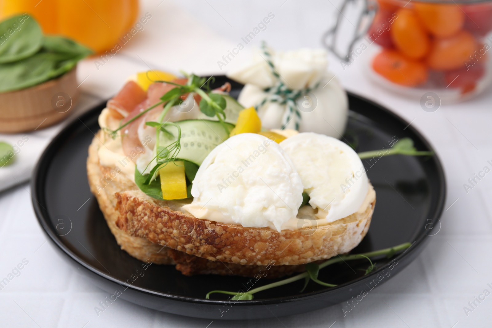 Photo of Tasty sandwich with burrata cheese, prosciutto and vegetables on white table, closeup