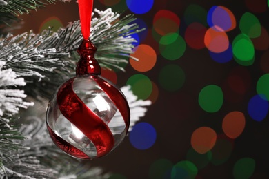 Photo of Beautiful holiday bauble hanging on Christmas tree against blurred festive lights, closeup. Space for text