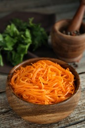 Photo of Delicious Korean carrot salad in bowl on wooden table