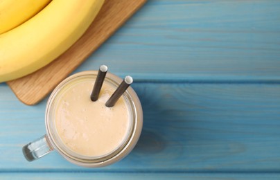 Mason jar with banana smoothie on light blue wooden table, flat lay. Space for text