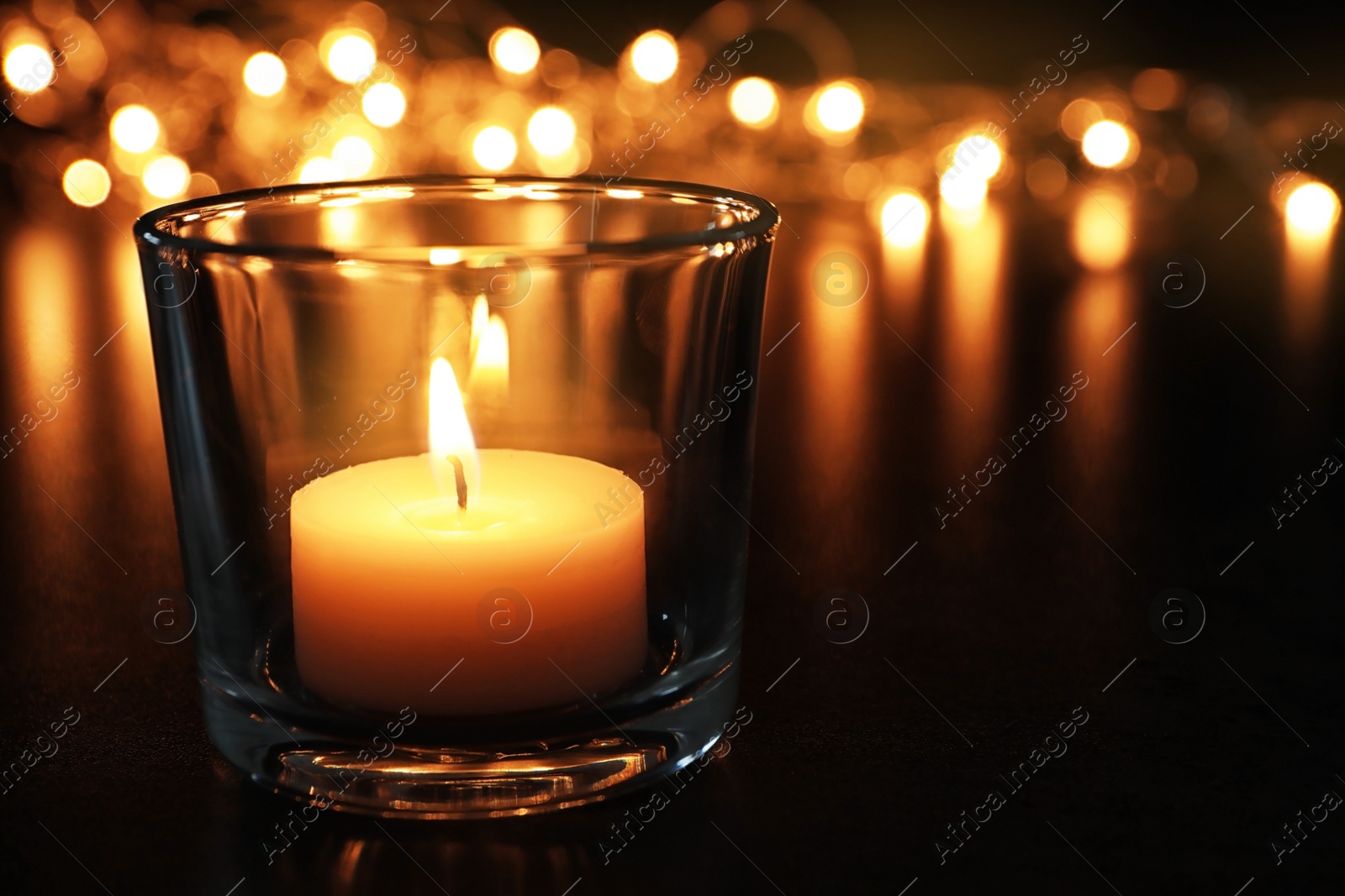 Photo of Wax candle burning on table in darkness, closeup