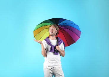 Man with rainbow umbrella on color background