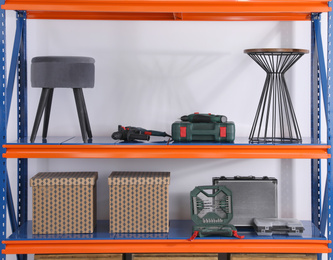 Photo of Metal shelving unit with household stuff and instruments on light background