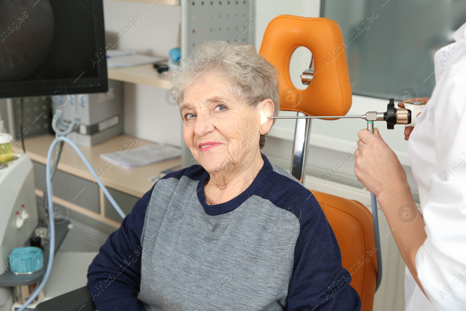 Photo of Professional otolaryngologist examining senior woman with endoscope in clinic. Hearing disorder