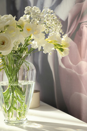 Photo of Beautiful bouquet with fresh freesia flowers in vase on table indoors