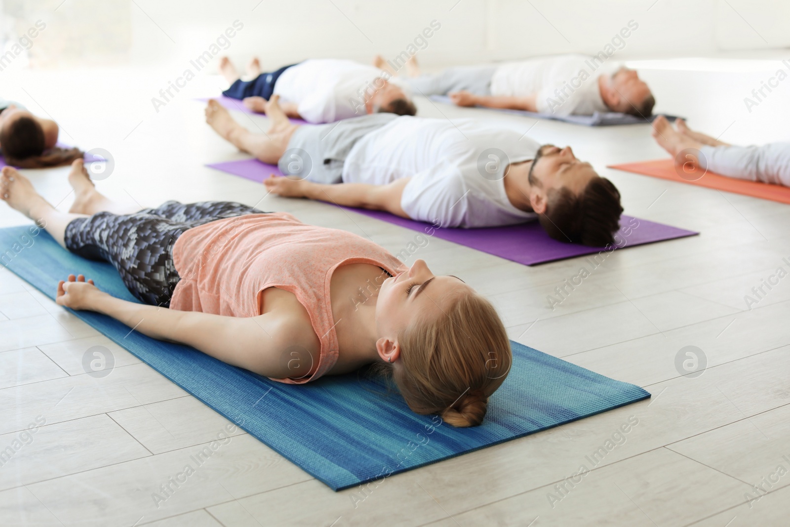 Photo of Group of people in sportswear practicing yoga indoors