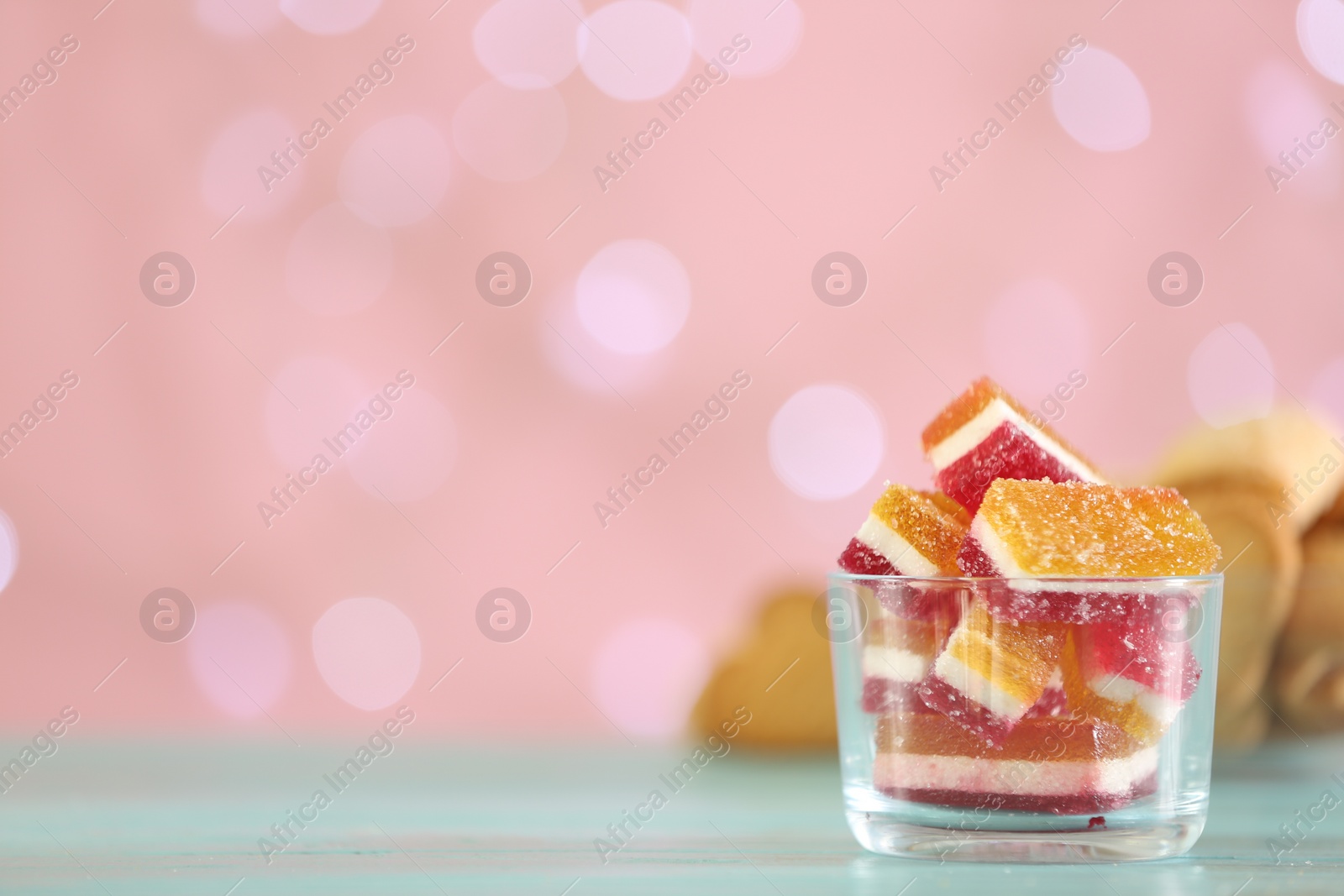 Photo of Delicious jelly candies in bowl on table against blurred background, closeup. Space for text